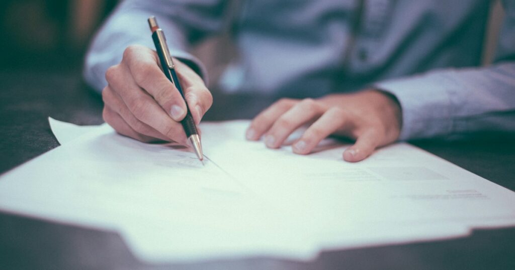 Dirigeant d'entreprise annotant un document à son bureau pour arbitrer sa rémunération