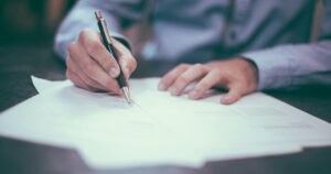 Dirigeant d'entreprise annotant un document à son bureau pour arbitrer sa rémunération